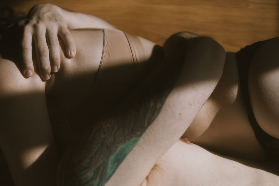Close-up of a couple hugging tightly with natural light and shadows across their skin