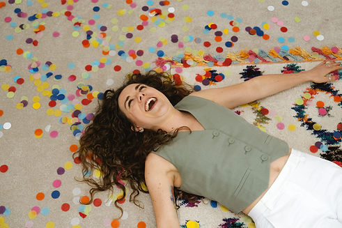 Woman laughing on the floor surrounded by colourful confetti during a personal branding shoot UK