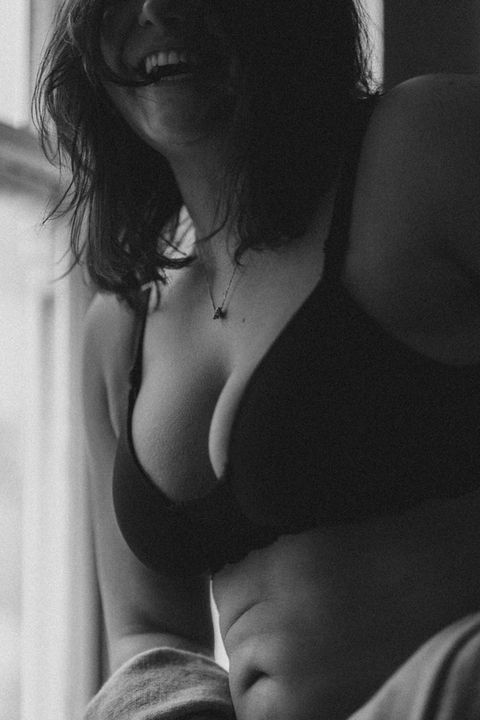 Black and white close up of a woman's chest and décolletage by a sunlit window