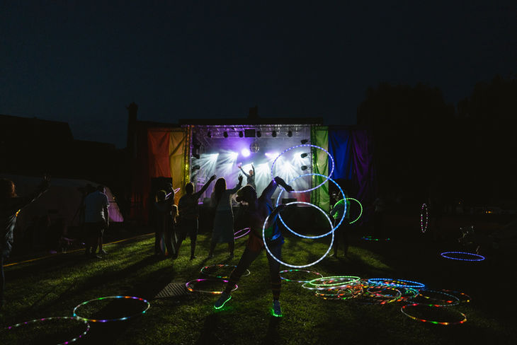 Crowd dancing with illuminated hula hoops outdoor during Ely Pride at night