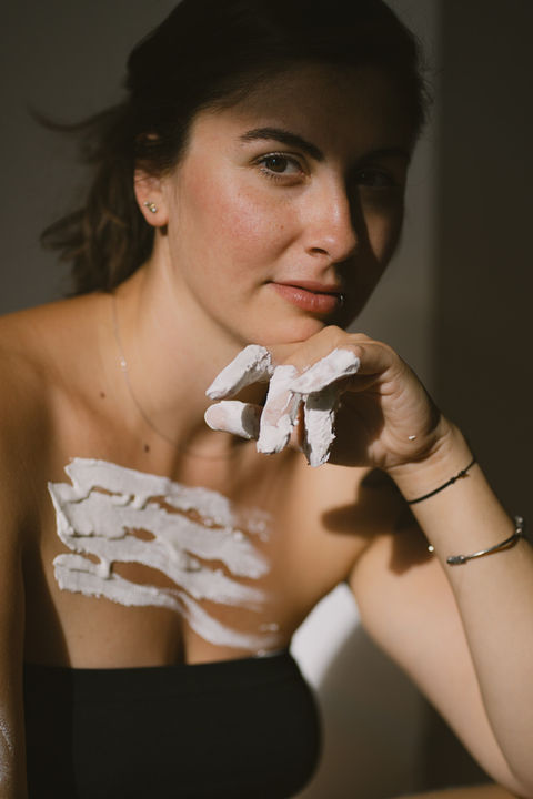 Woman with white paint on her fingers and chest looking at the camera