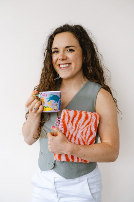 Woman smiling while holding a mug and a striped fluffy notebook