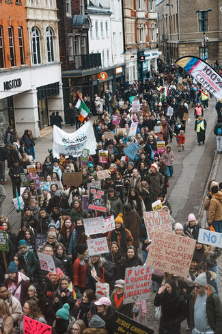 Aerial view of a large crowd marching with banners at a women's rights protest by a protest photographer London