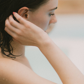 Detail of Poppy positioning her wet hair behind her eras