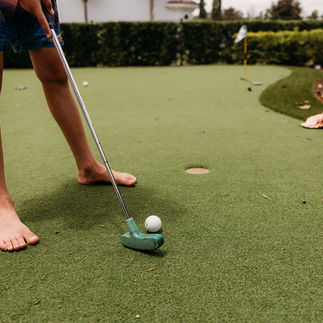 Child playing golf on a vacation day during a relaxed family photography session