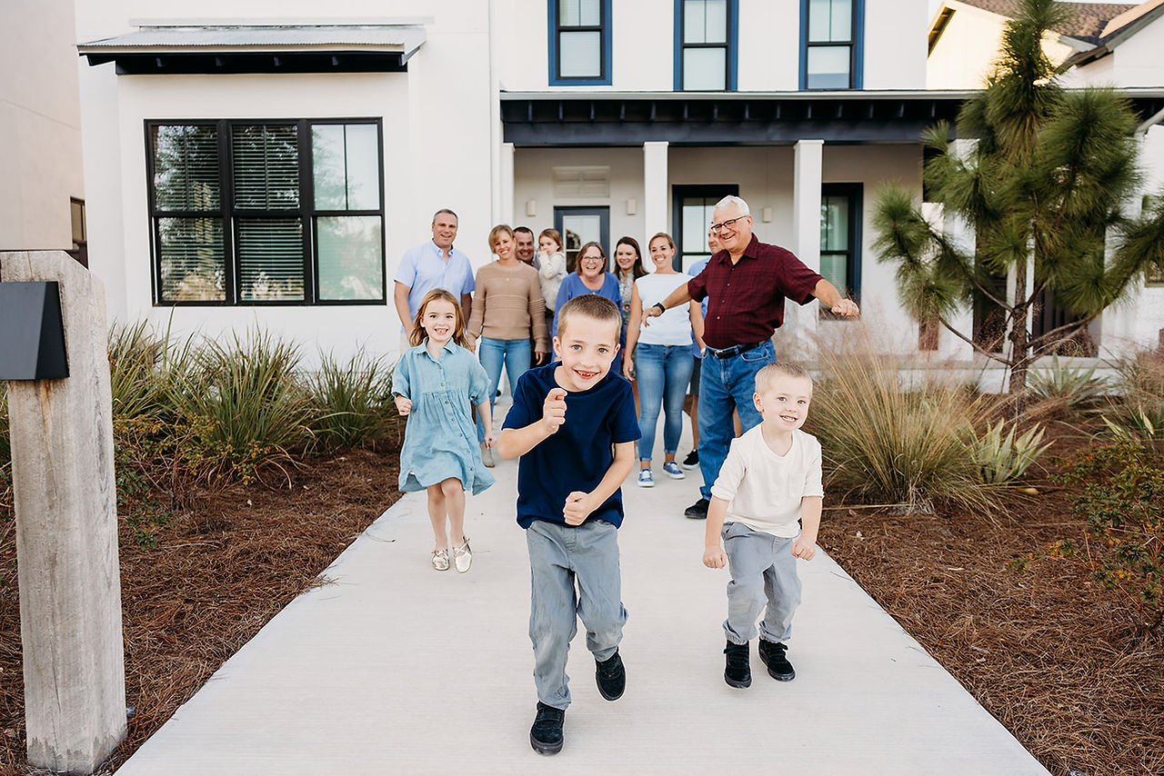Extended family walking and laughing together outside a rental home during a lifestyle photography session