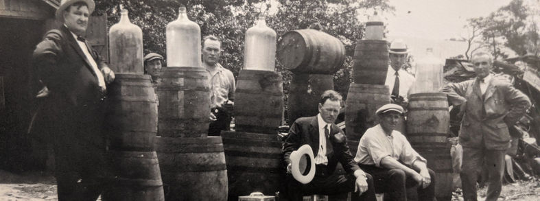 Image of men standing around seized barrels of alcohol