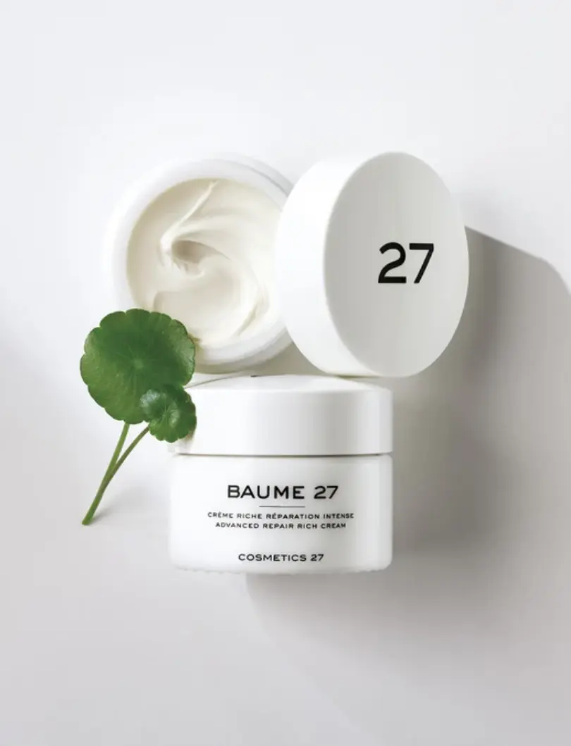 Open jar of Cosmetics 27 Baume 27 advanced repair rich cream with centella asiatica leaf on a white background, showing texture and minimalist packaging.