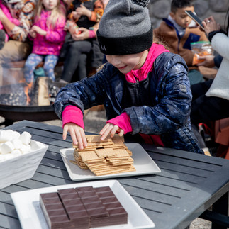 A young child makes a s'more at Planet Cleanup 2023.