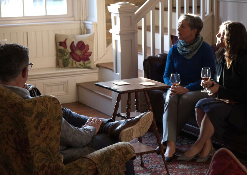 A group of hotel guests enjoying glasses of wine sitting on couches on the main floor