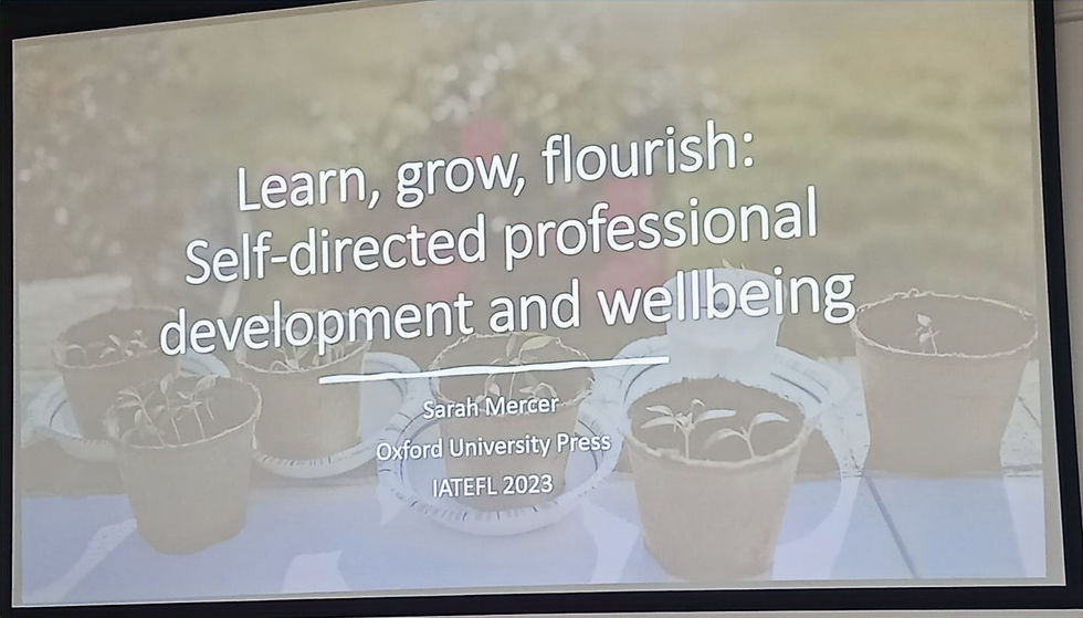Quote from Sarah: "Learn, grow, flourish> Self-directed professional development and wellbeing over a picture of germinating plants in pots on a table in the garden