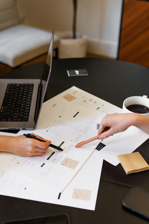 Two team members collaborate over a conference table point out details on printed marketing materials