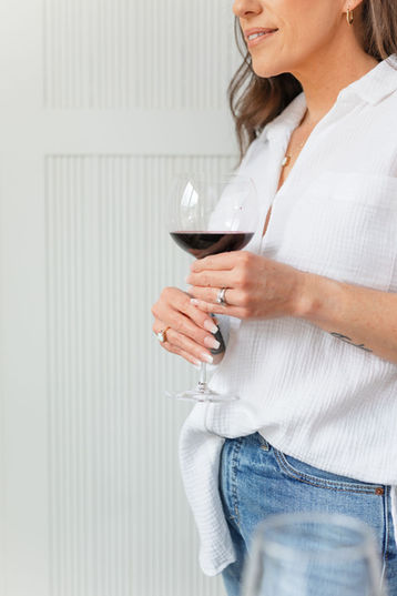 A woman holds a wine glass while looking out the window - Light and Bright Personal Branding Photos NOVA
