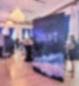 a party in a ballroom with chandeliers. Giant versions of the book Adrift by Lisa Brideau decorate the room. people are mingling.