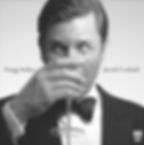 Gregg Arthur in a tuxedo sipping a martini