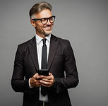 A smiling senior manager in a business suit holding a smartphone, illustrating professional leadership workshops for mental health and team support.