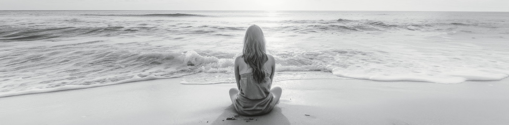 Schwarz-weißes Foto einer Person, die am Strand meditiert und den Wellen zugewandt ist; darüber der Text: „Wahre Kraft beginnt innen – wenn Ihr Geist klar ist…“
