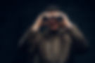 young-traveler-looks-into-camera-with-binoculars-smiles-black-background.jpg