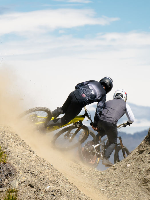 Pivot Firebird auf einem Enduro-Trail mit zwei Fahrern in einer staubigen Kurve.