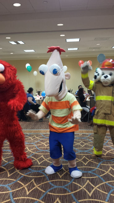 A Phineas Flynn mascot character dancing alongside Elmo and Marshall at an indoor party.