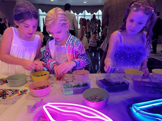 Kids making custom jewelry at a bead station
