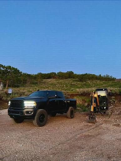 Black 2022 dodge ram sitting next to a backhoe on a job site