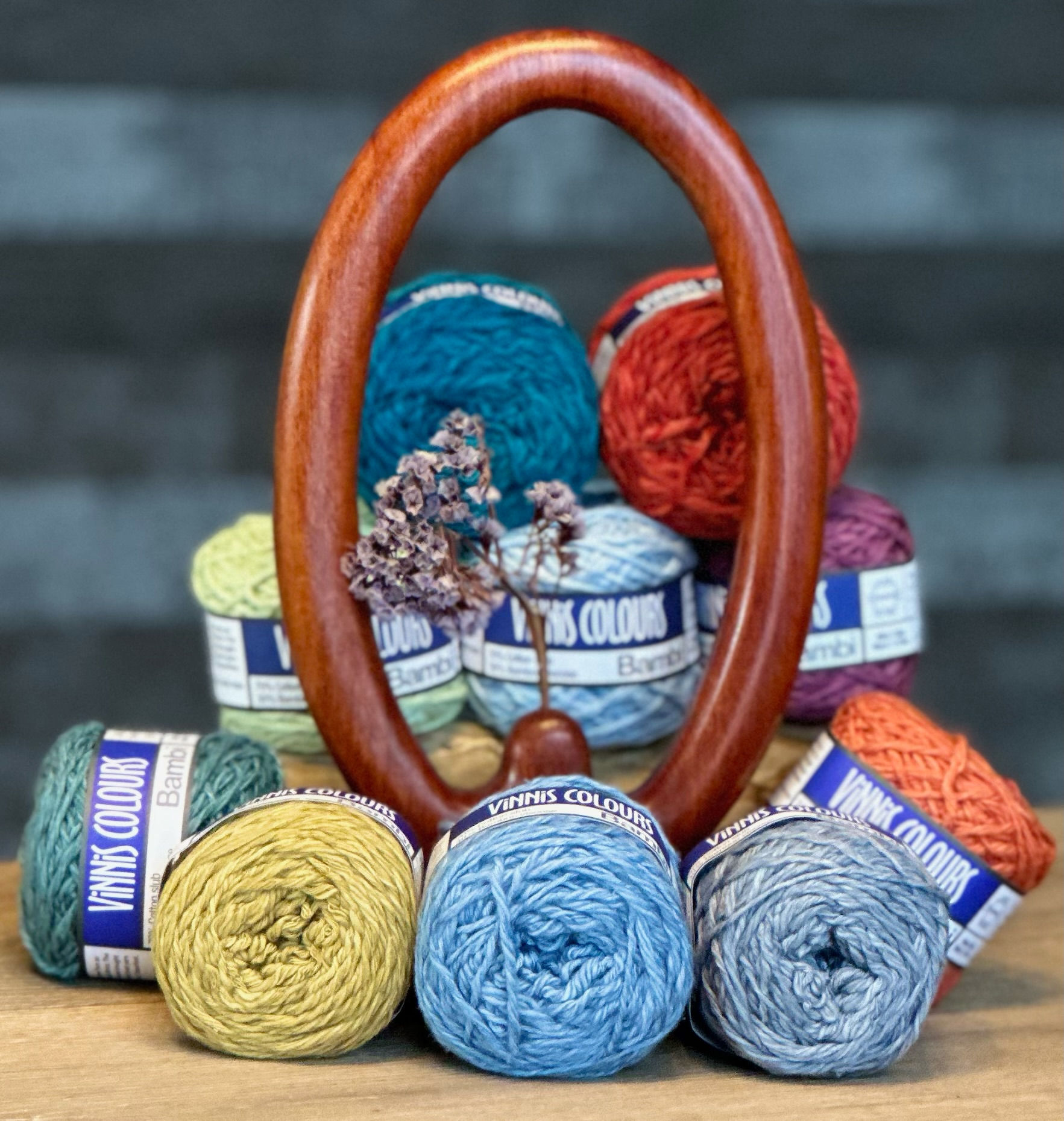 10 balls of Bambi balls of yarn around a wooden stand with a single dried flower