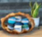 7 balls of Tori yarn in a wooden basket next to a plant