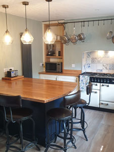 A kitchen featuring a large wooden island with bar stools and a range cooker