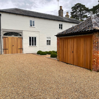 Wooden double garage doors on a detached outbuilding alongside a gravel driveway
