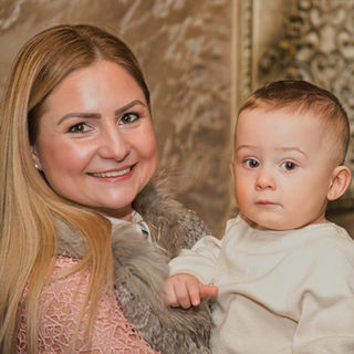 A mother carrying a young child in formal wear