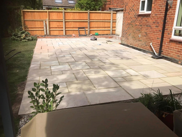 Newly installed light stone patio in a residential backyard