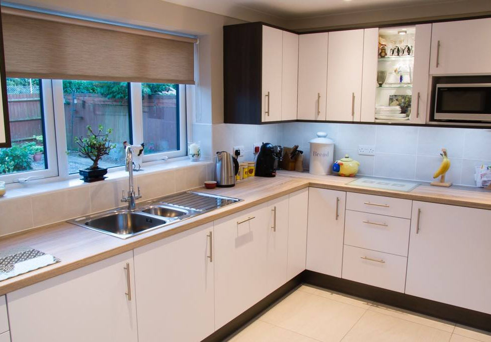 A modern, L-shaped kitchen featuring a combination of white and dark cabinetry