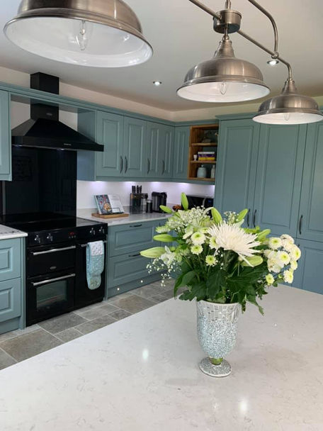 A modern kitchen featuring blue shaker-style cabinets, a white quartz countertop