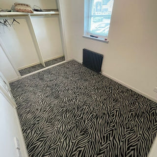 A small bedroom with an animal print carpet