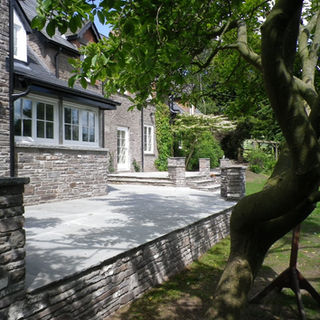 A beautifully landscaped garden with a stone-paved patio area leading up to a house