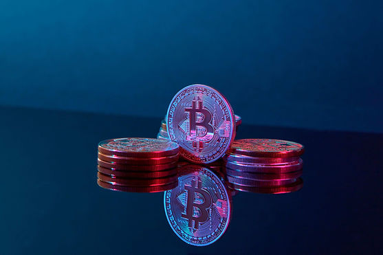 Stacks of Bitcoin coins glowing pink and blue on a reflective dark surface