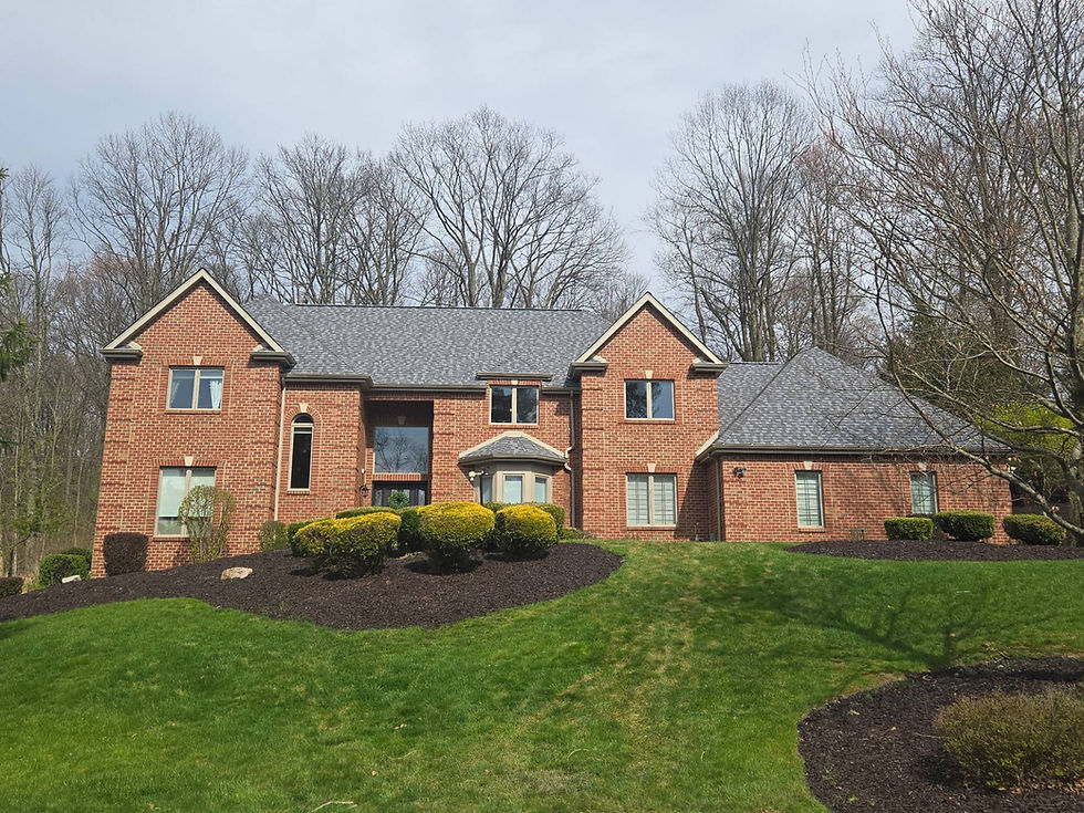 Large red brick house with green lawn and trees