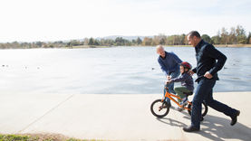 Photo of two men and a child riding a bicycle.