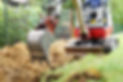 Workman using a mini digger to excavate a hole for water pipes in the garden. Czech republ
