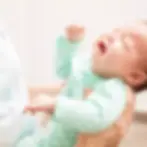 Mulher segurando um bebê chorando.