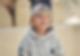 Lachender Junge mit Baseballkappe und Hoodie, draußen in die Ferne blickend.