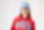 Mädchen in blauer Mütze und rotem "MANHATTAN" Hoodie, blickt nach vorne.