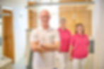 Arzt mit Team im Wartebereich, in weißen Hemden und rosa T-Shirts.