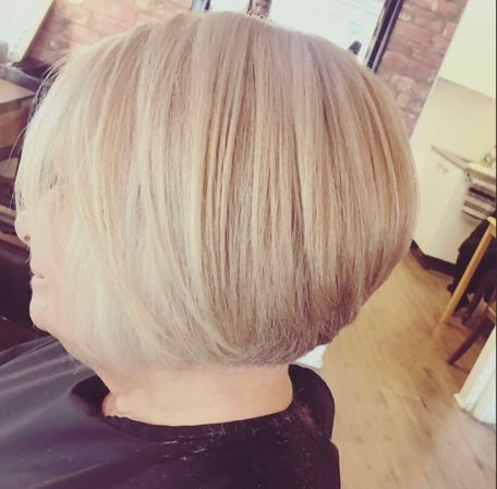 Side view of woman sat in hairdressers with blonde perm