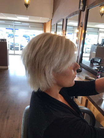 Side view of woman sat in hairdressers with blonde bob 