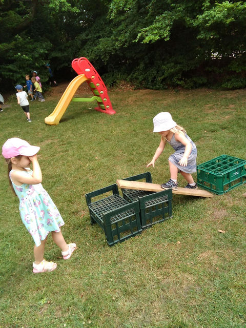 Two young girls playing outside in summer dresses and hats