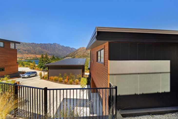 a fence surrounds a house with mountains in the background