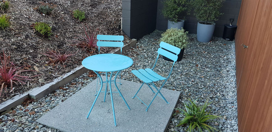 a blue table and two blue chairs on a gravel area