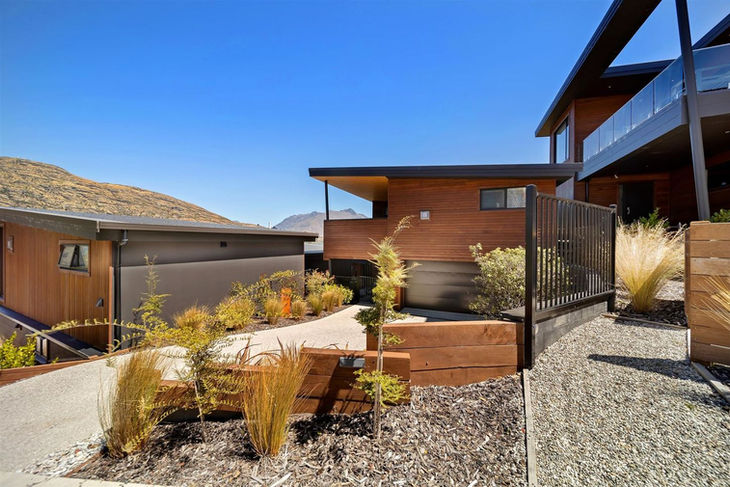 a house with a lot of plants and trees in front of it